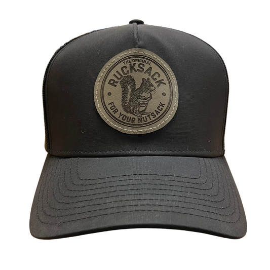 Nut Ruck black trucker hat with grey leather patch laser engraved with "the original rucksack for your nutsack" artwork and slogan.