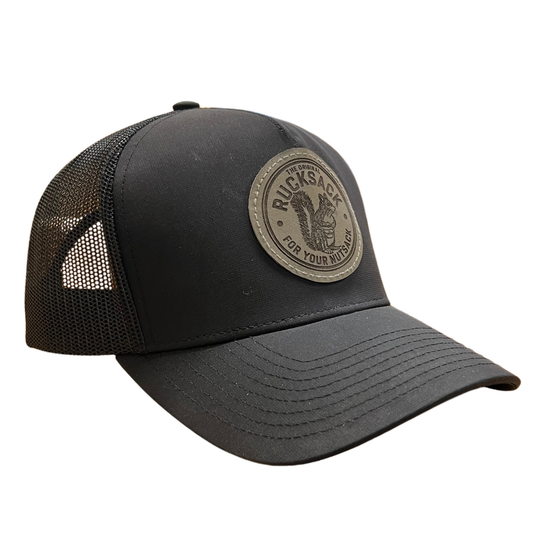 Nut Ruck black trucker hat with grey leather patch laser engraved with "the original rucksack for your nutsack" artwork and slogan.